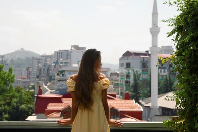 Young woman standing on balcony, back view