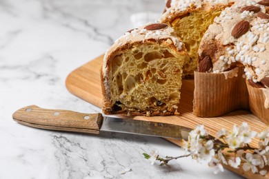 Photo of Delicious Italian Easter dove cake (traditional Colomba di Pasqua) and knife on white table, closeup