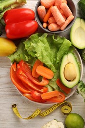 Photo of Healthy diet. Fresh vegetables and measuring tape on light wooden table, flat lay