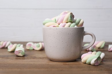 Photo of Ceramic cup with colorful marshmallows on wooden table