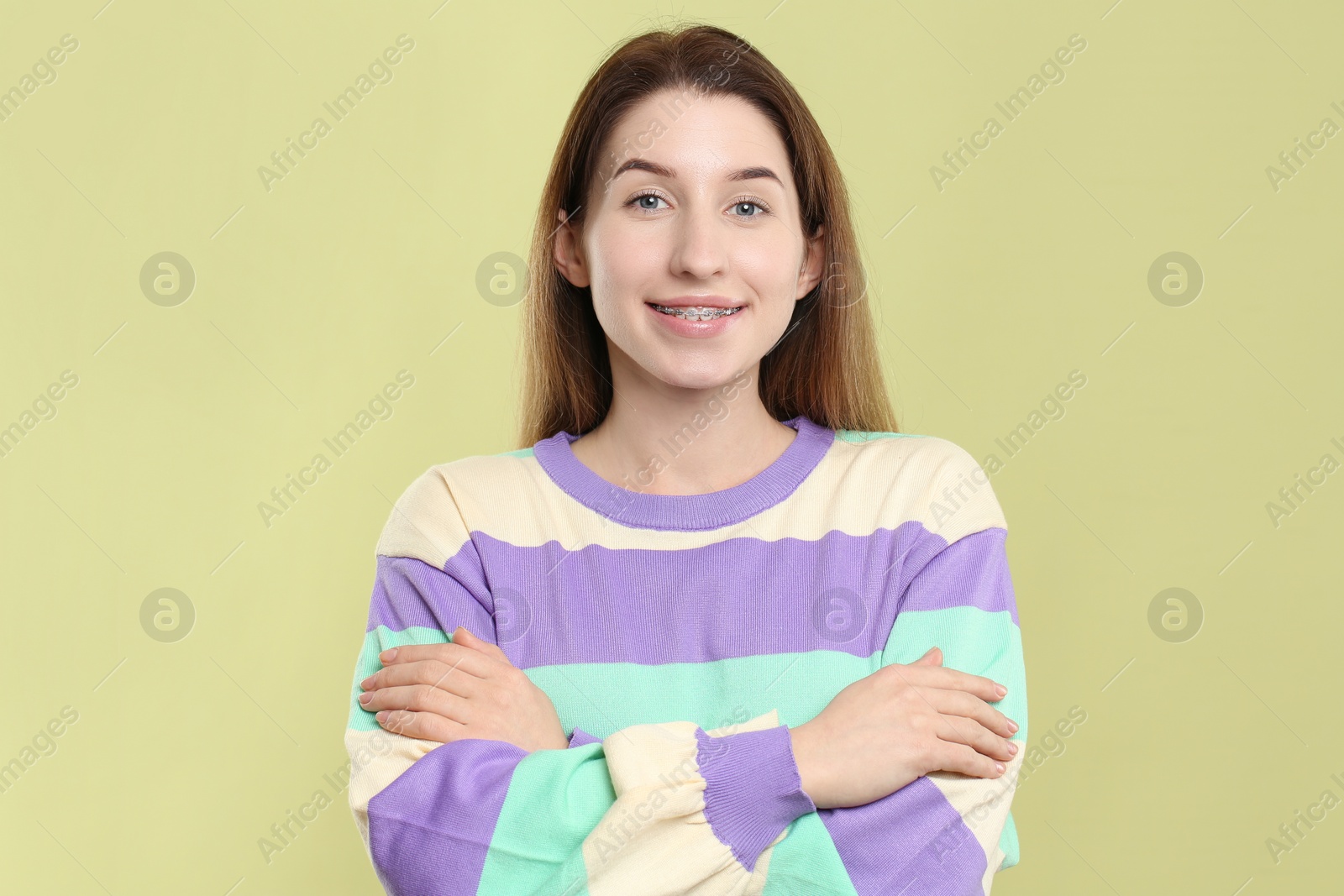 Photo of Portrait of smiling woman with dental braces on light green background