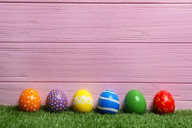 Photo of Decorated Easter eggs on green grass. Space for text