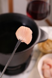 Photo of Fondue fork with raw piece of meat on blurred background
