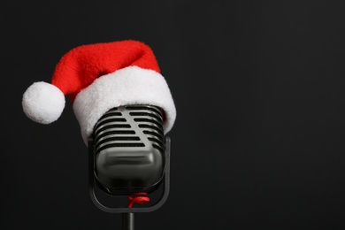 Retro microphone with Santa hat on black background, space for text. Christmas music