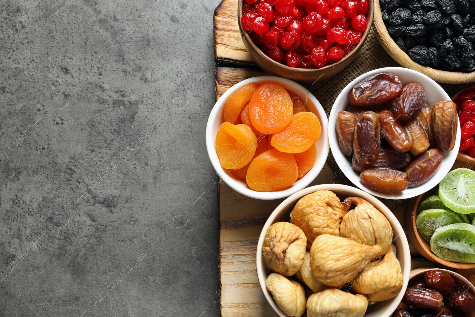 Photo of Bowls of different dried fruits on grey background, top view with space for text. Healthy food