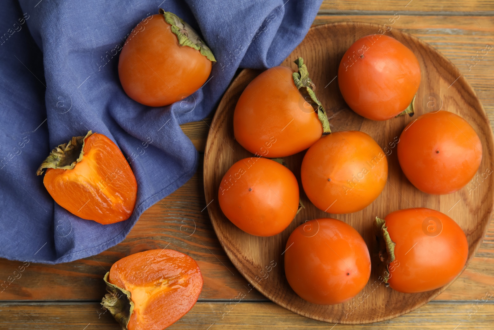 Photo of Tasty ripe persimmons on wooden table, flat lay