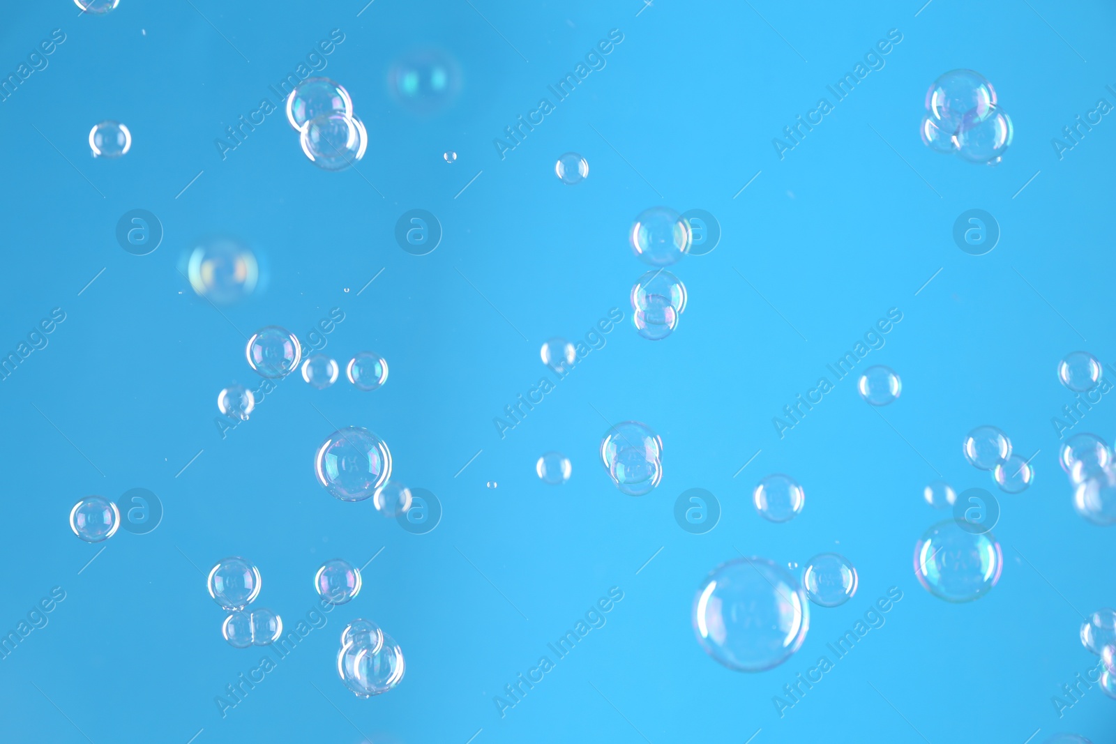 Photo of Beautiful transparent soap bubbles on light blue background