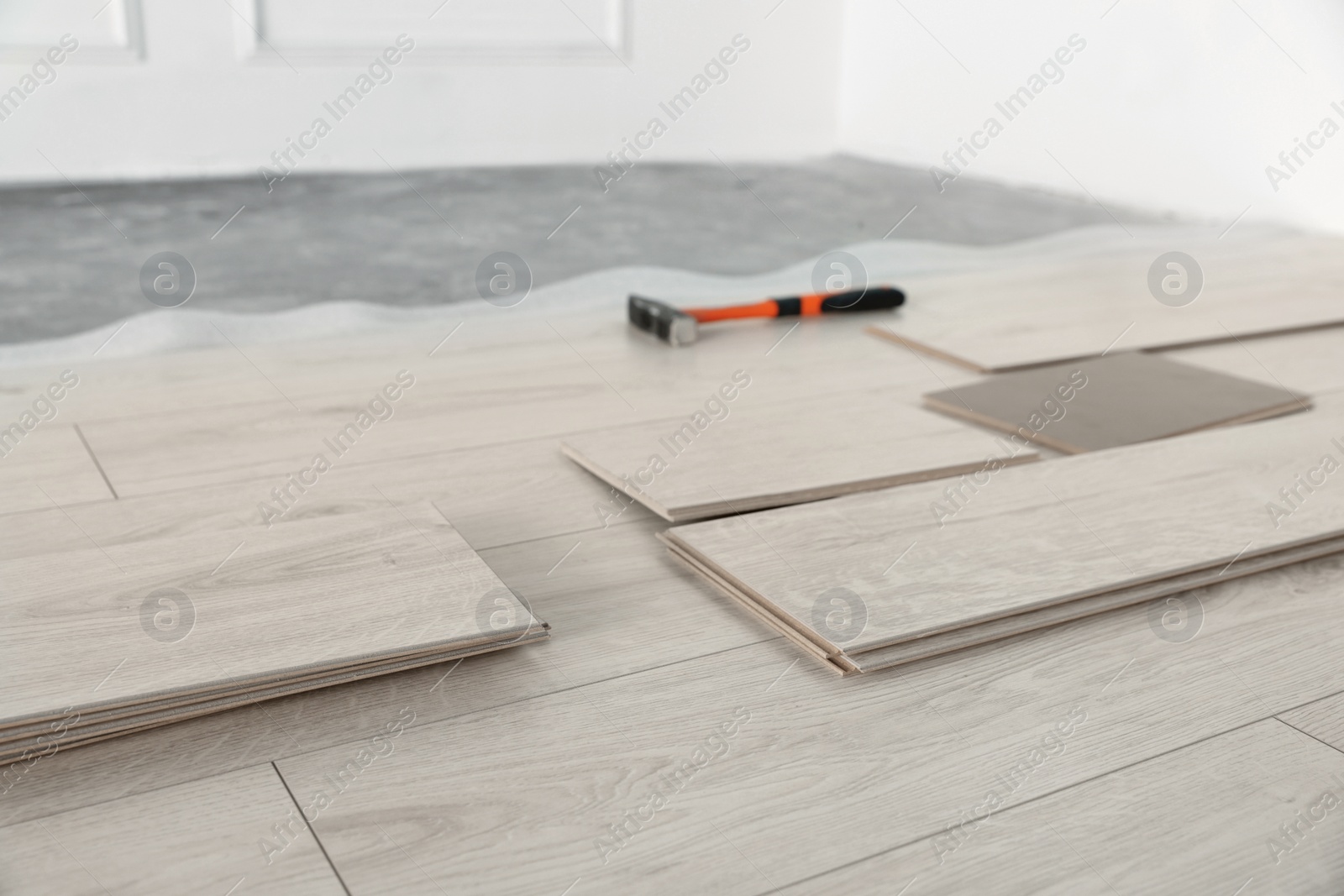 Photo of Parquet planks and hammer on floor in room prepared for renovation