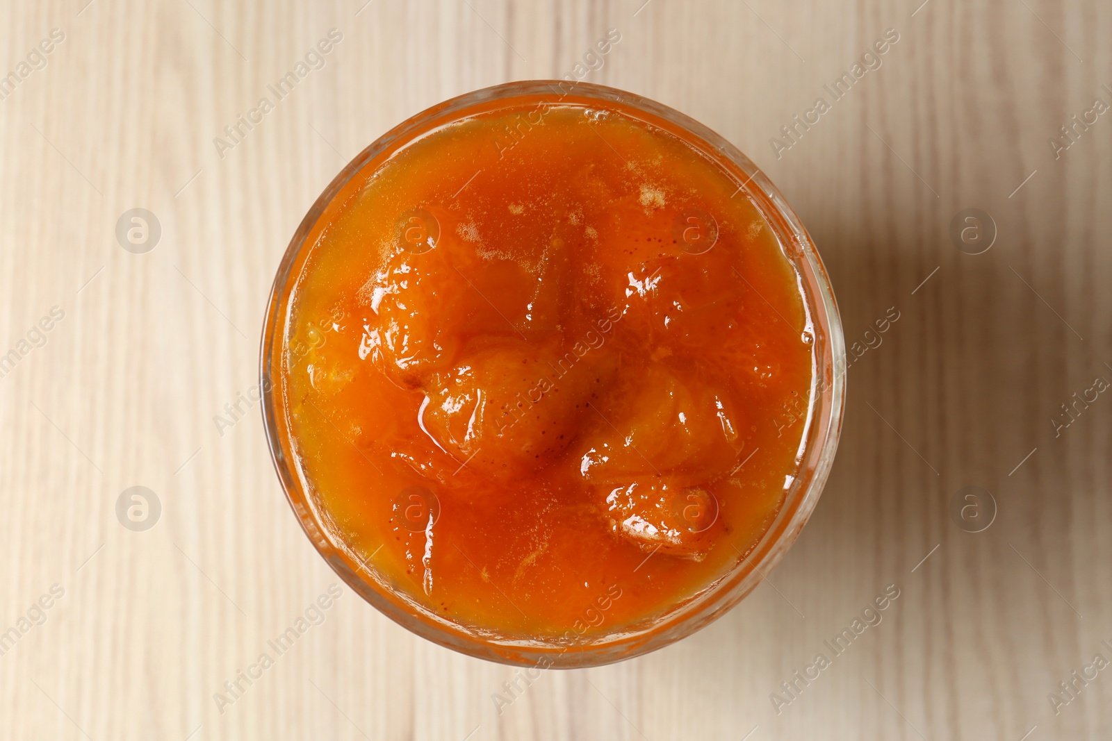 Photo of Dessert bowl with delicious apricot jam on white wooden table, top view