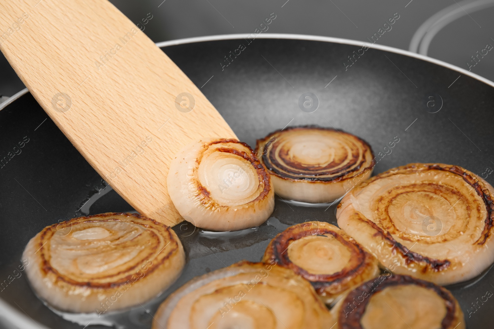 Photo of Cooking onion rings in frying pan, closeup