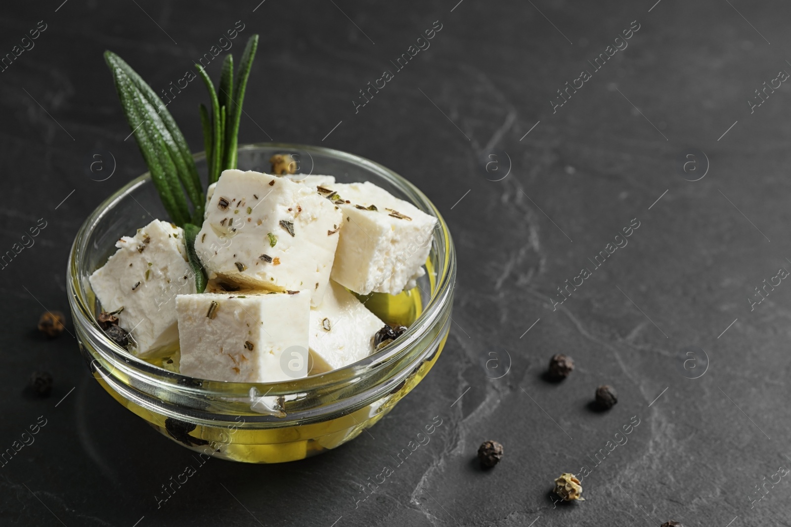 Photo of Pickled feta cheese in bowl on dark grey table. Space for text