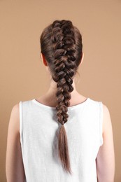 Photo of Woman with braided hair on light brown background, back view