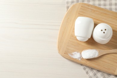 Photo of Spice shakers with salt on white wooden table, top view. Space for text