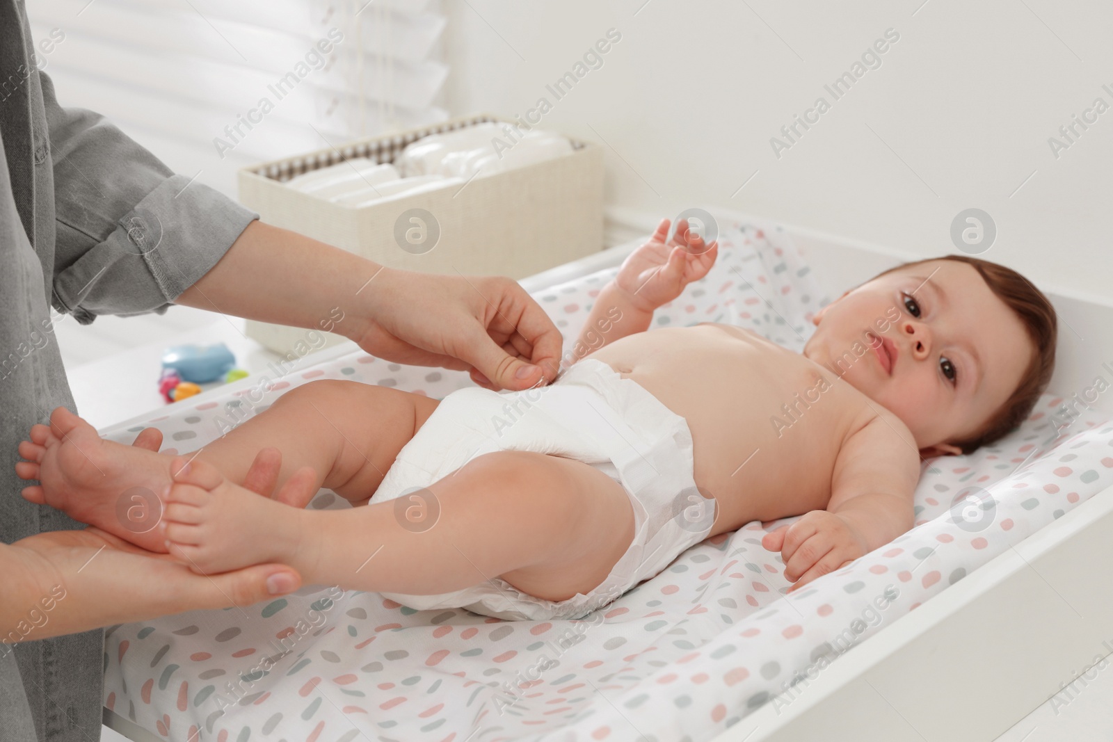 Photo of Mother changing baby's diaper on table at home, closeup