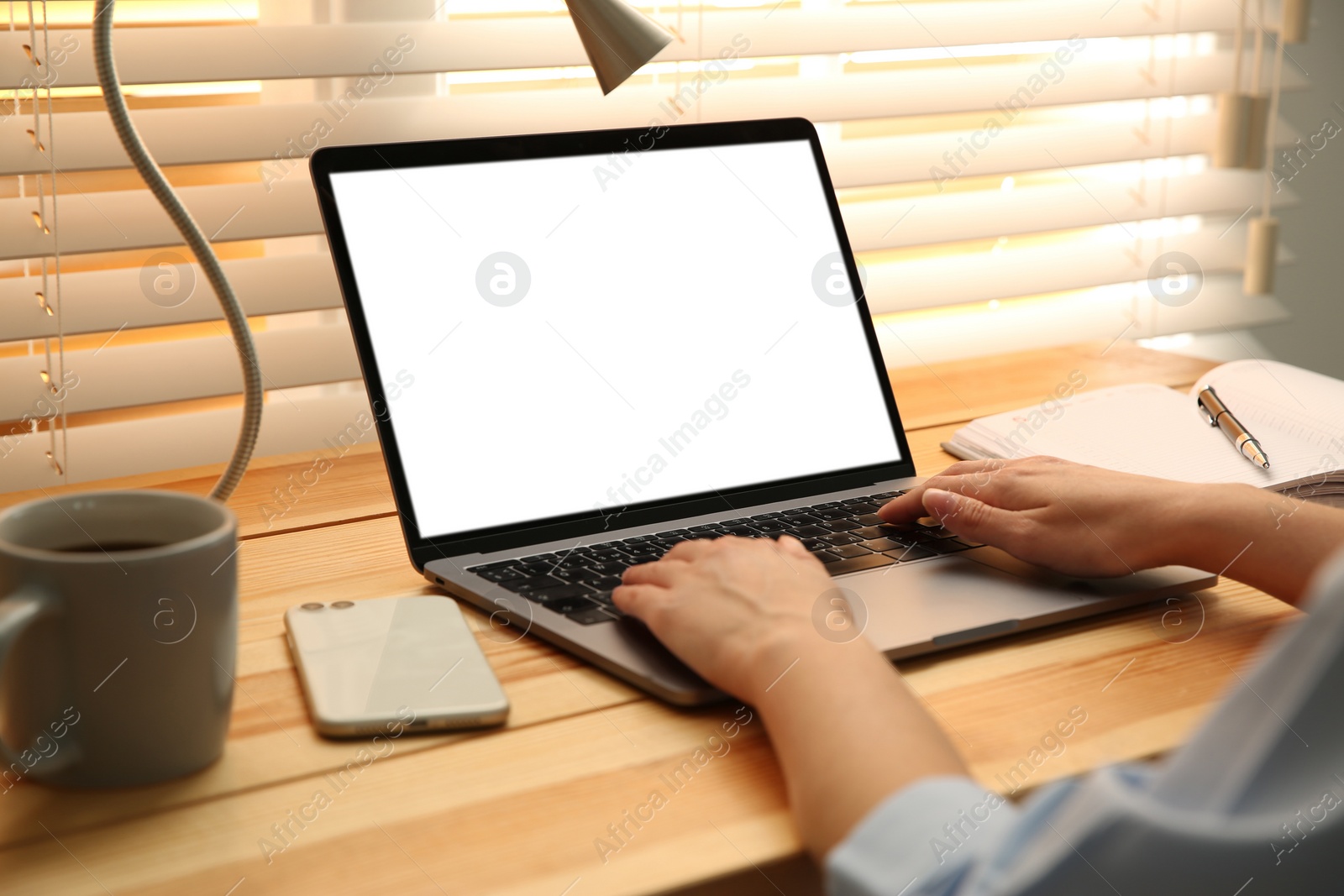 Photo of Woman working with modern laptop at wooden table, closeup. Space for design