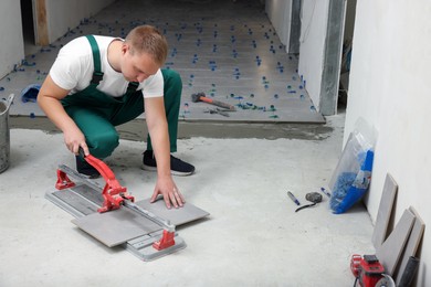 Photo of Worker using manual tile cutter in room