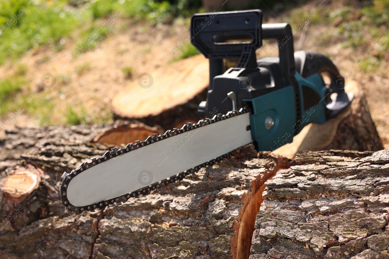 Photo of Modern electric saw and wooden log outdoors