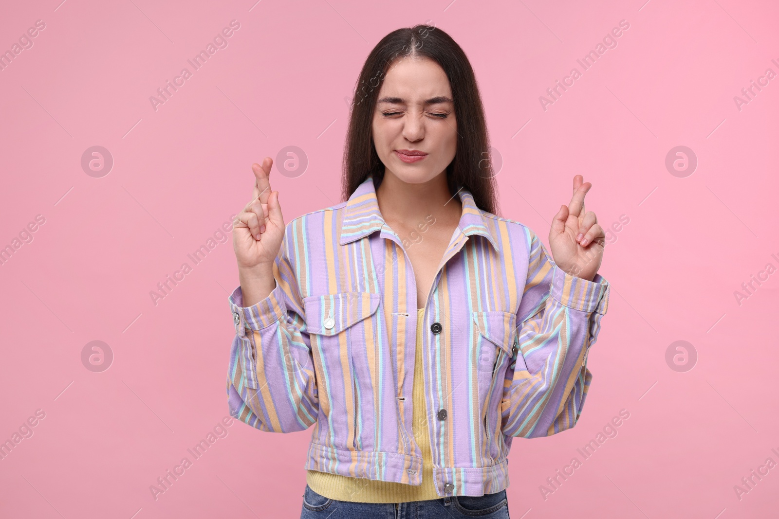 Photo of Beautiful woman crossing her fingers on pink background