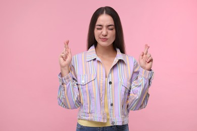 Photo of Beautiful woman crossing her fingers on pink background