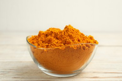 Photo of Aromatic saffron powder in bowl on white wooden table
