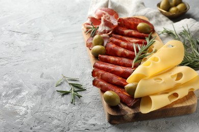 Photo of Charcuterie board. Delicious cured ham, cheese, sausage, olives and rosemary on light grey table, space for text