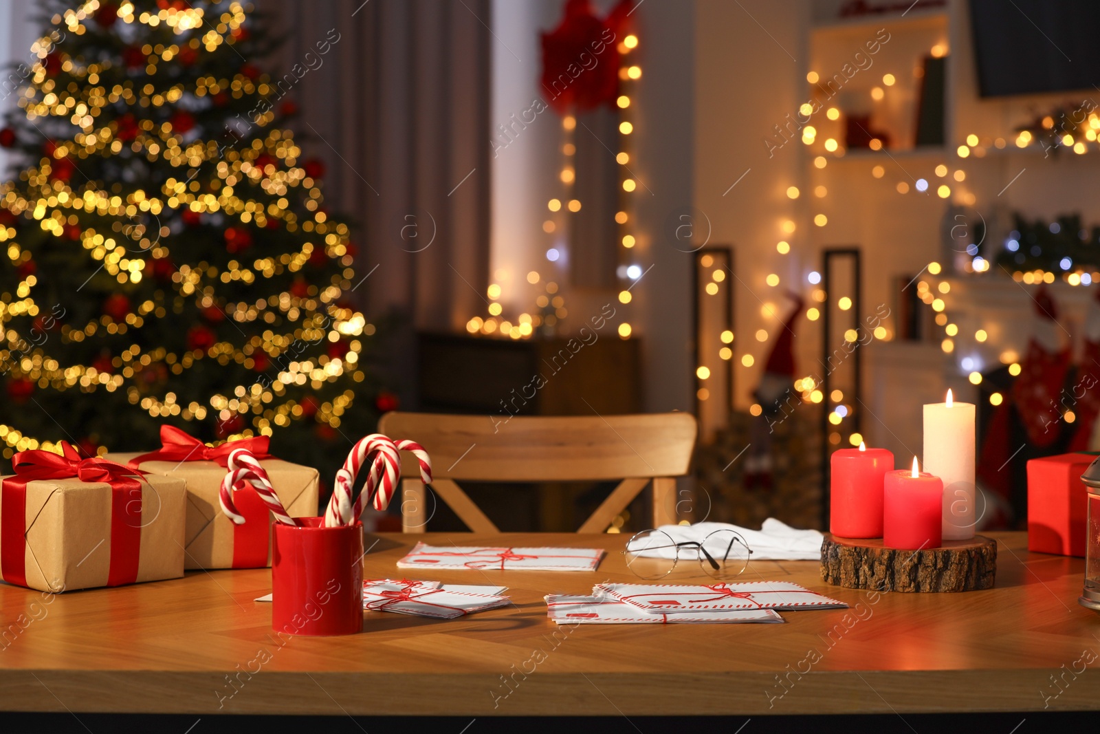 Photo of Santa's Claus workplace. Gift boxes, letters and candy canes on table in room with Christmas decor