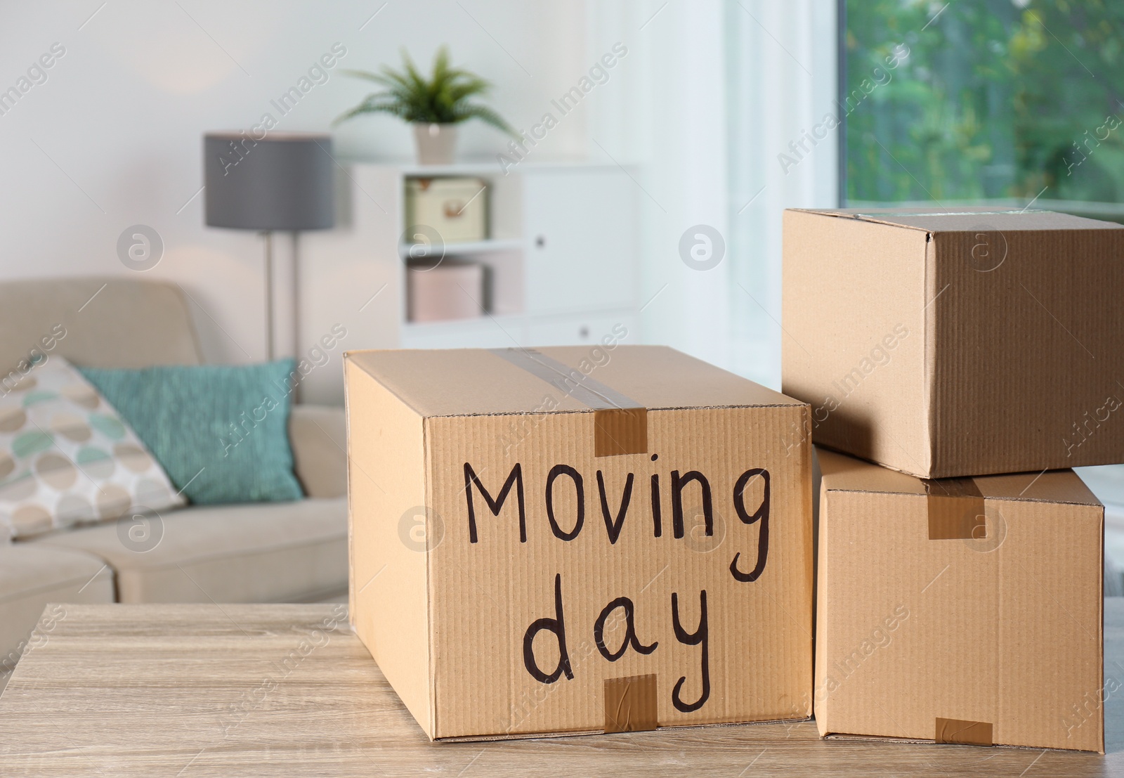 Photo of Cardboard boxes on table against blurred background. Moving day