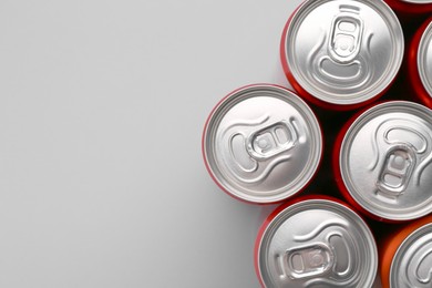 Photo of Energy drink in cans on grey background, top view. Space for text