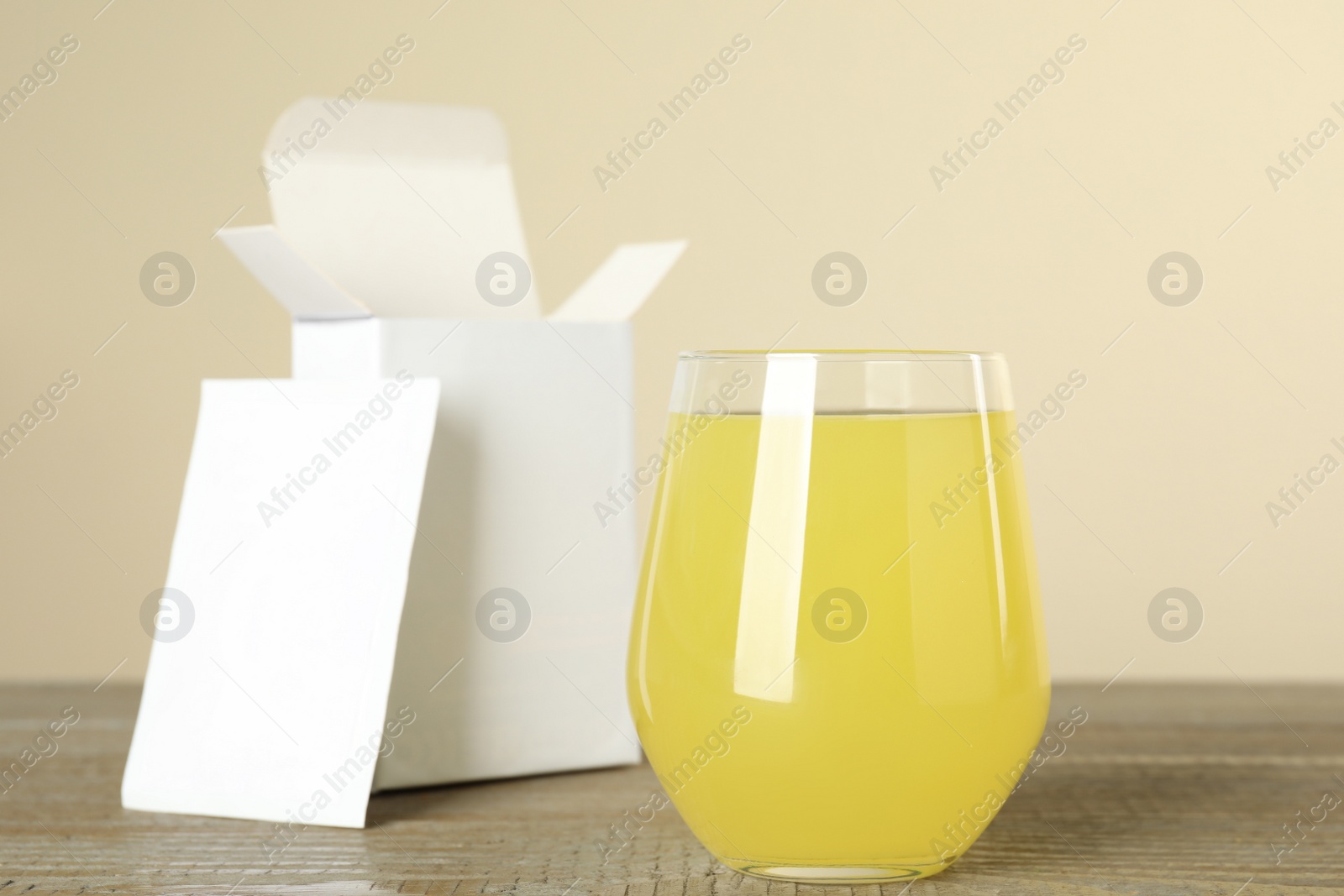 Photo of Glass with dissolved drug and medicine sachet on wooden table