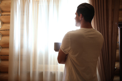 Man with drink near window indoors. Lazy morning