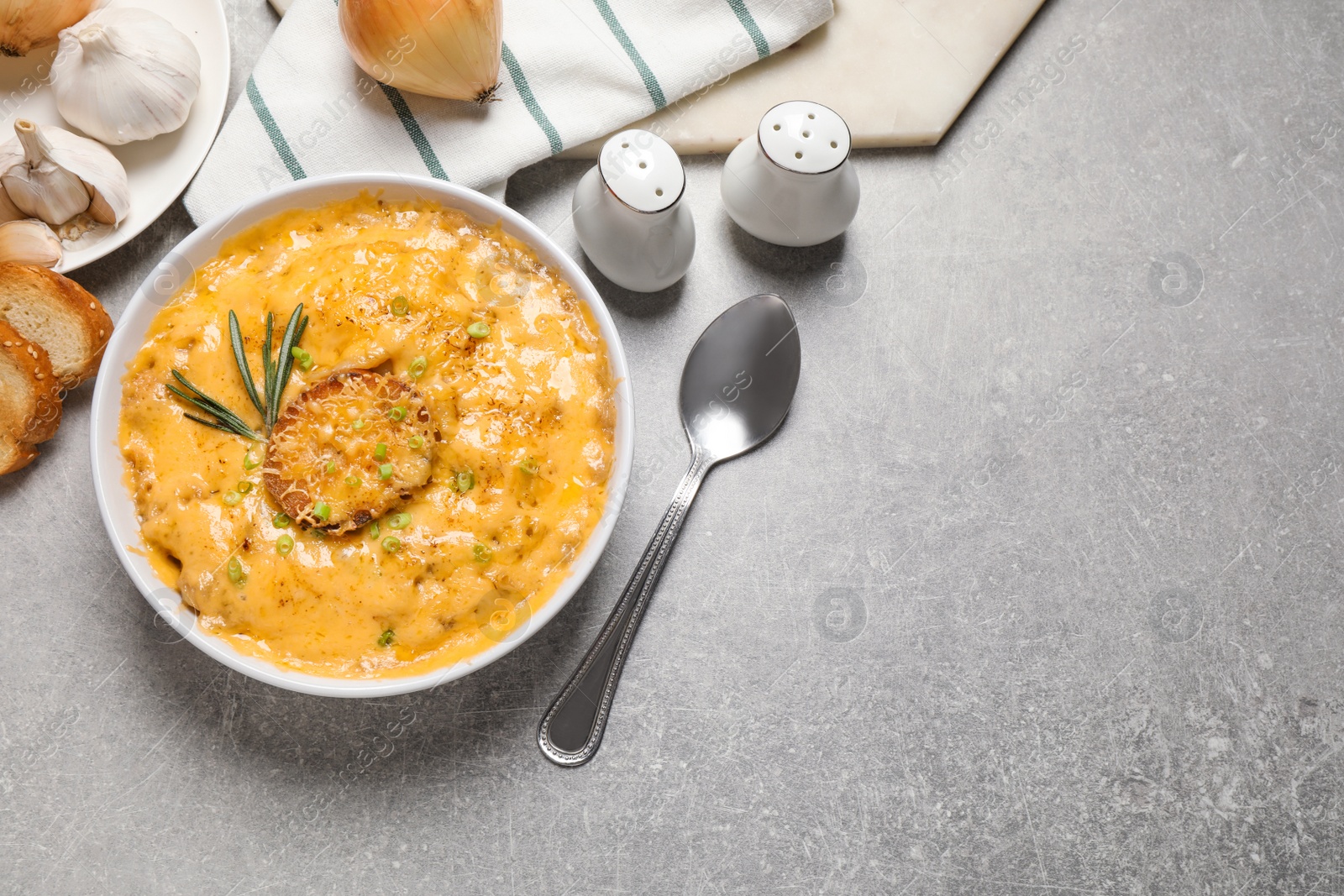 Photo of Tasty homemade French onion soup on grey table, flat lay. Space for text