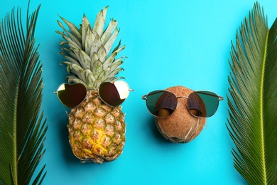 Photo of Pineapple and coconut with sunglasses on blue background, flat lay