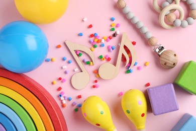 Photo of Baby song concept. Wooden notes, kids maracas and toys on pink background, flat lay