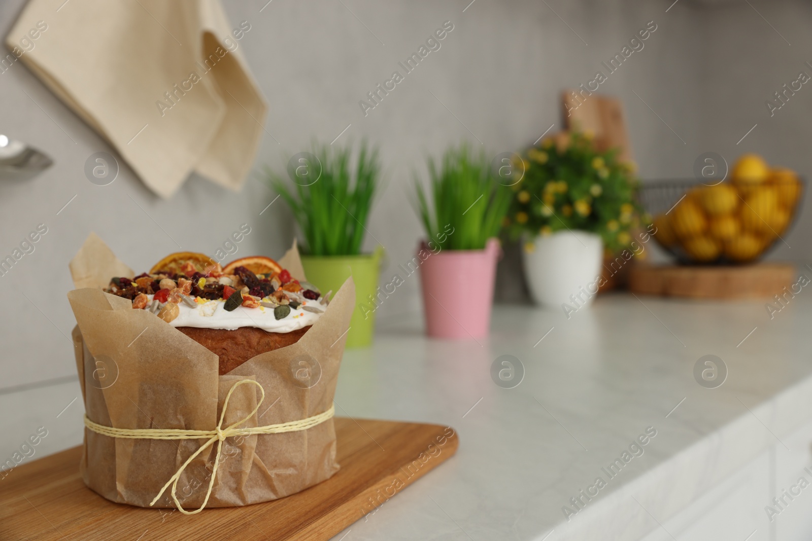Photo of Traditional Easter cake with dried fruits on table in kitchen, space for text