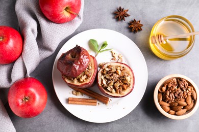 Tasty baked apples with nuts, honey and spices on gray table, flat lay