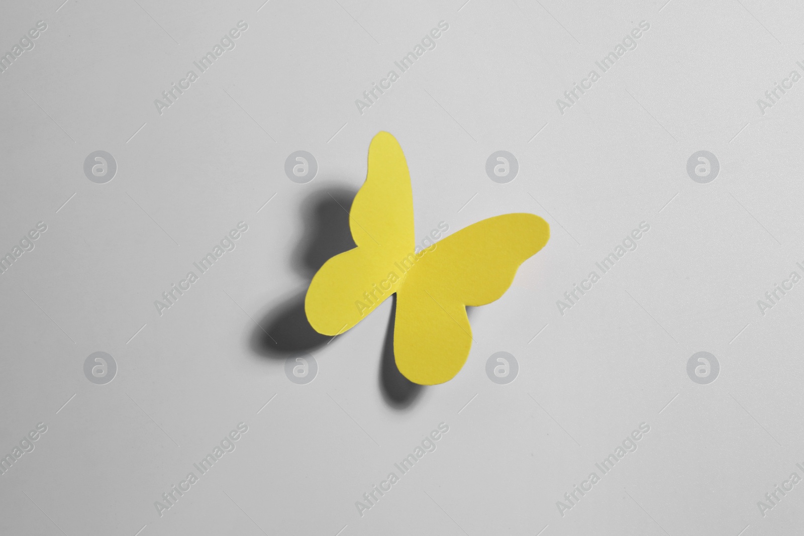 Photo of Yellow paper butterfly on light background, top view