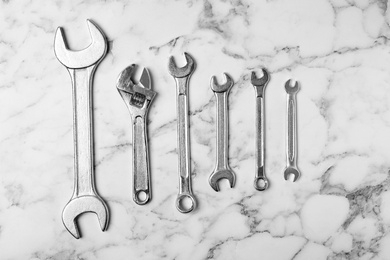 New wrenches on marble background, top view. Plumber tools