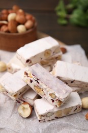 Photo of Pieces of delicious nutty nougat on white parchment paper, closeup
