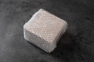 Photo of Cardboard box covered with bubble wrap on dark grey table