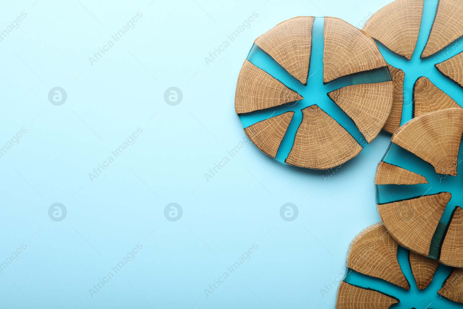 Photo of Stylish wooden cup coasters on light blue background, flat lay. Space for text