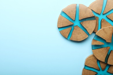 Stylish wooden cup coasters on light blue background, flat lay. Space for text