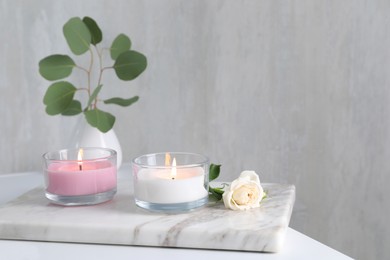 Burning candles and beautiful rose on white table