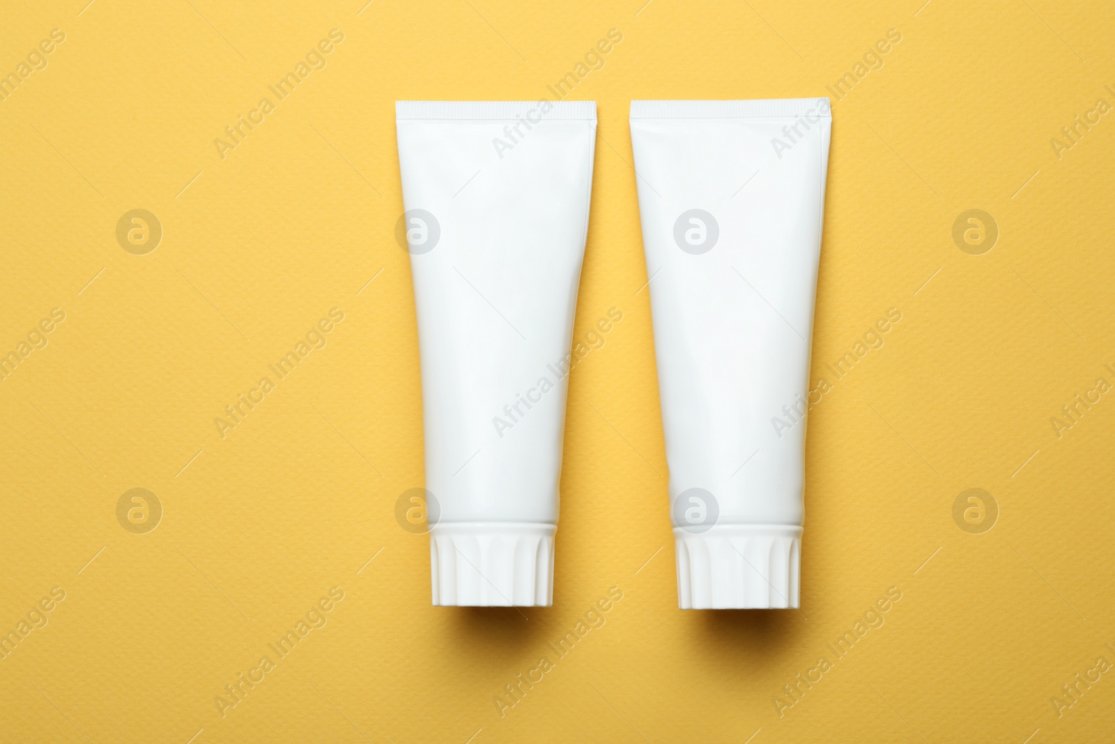 Photo of Blank tubes of toothpaste on color background, top view