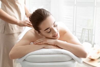 Photo of Young woman having body scrubbing procedure with sea salt in spa salon