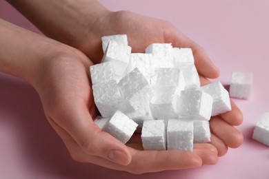 Photo of Woman with handful of styrofoam cubes on pink background, closeup