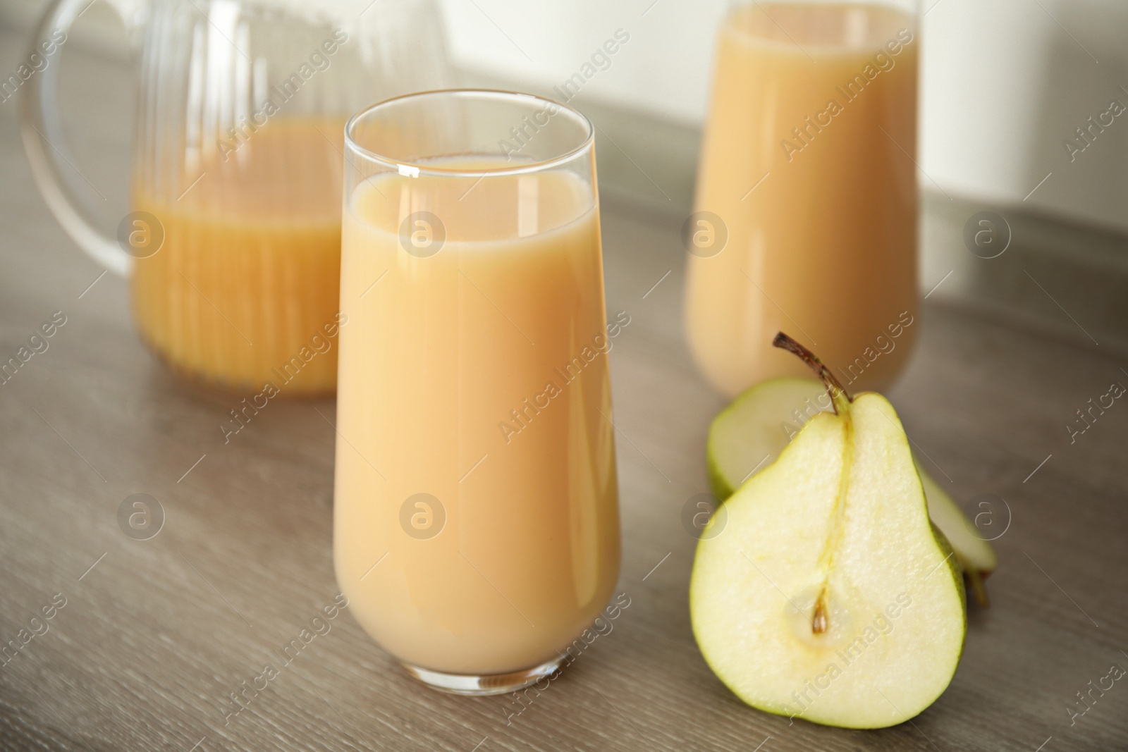 Photo of Tasty pear juice and cut fruit on wooden table, closeup