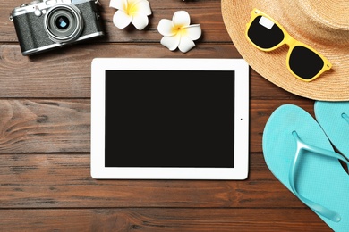 Flat lay composition with beach objects and tablet on wooden background