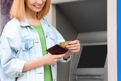 Photo of Woman with credit card near cash machine outdoors, closeup