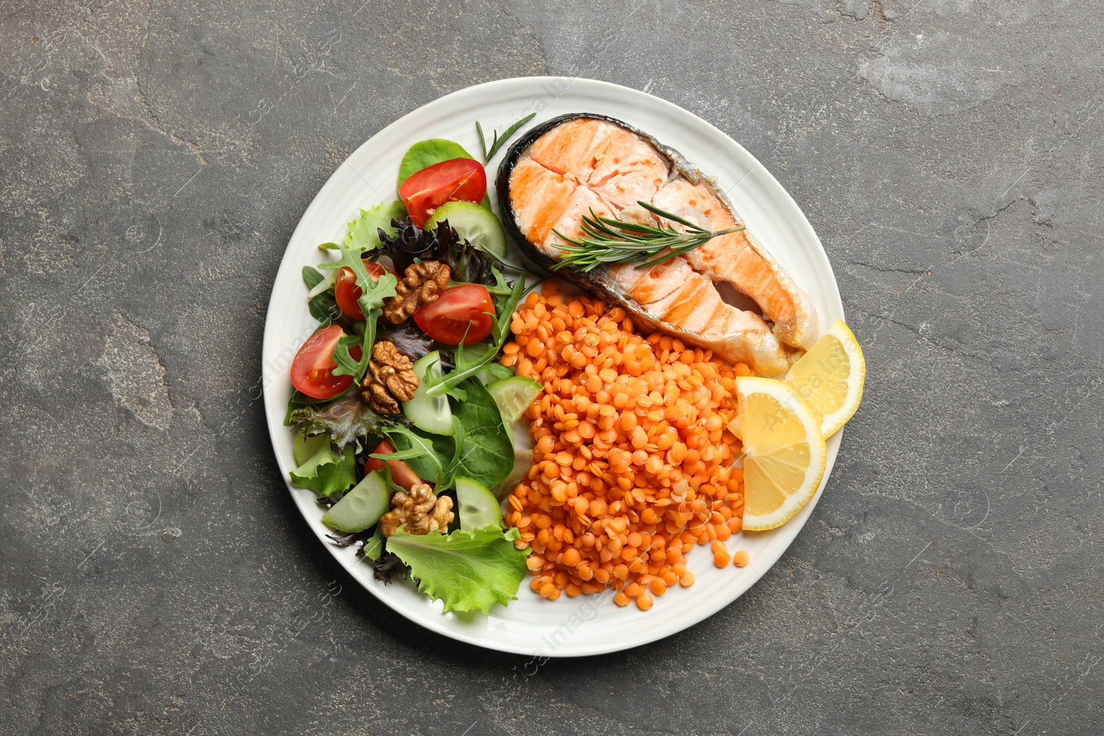 Photo of Plate with healthy food high in vegetable fats on grey textured table, top view