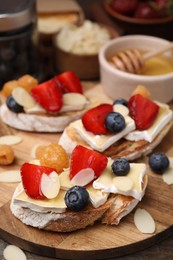 Photo of Tasty sandwiches with brie cheese, fresh berries and almond flakes on table